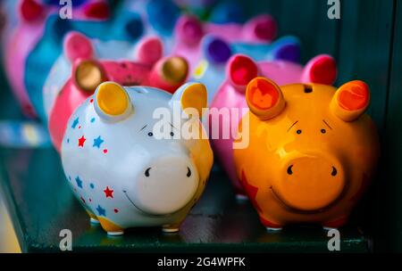 Coloridos imitadores cerámicos en forma de cerdo en el estante de madera Foto de stock