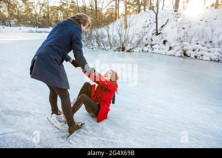 Novio sosteniendo manos de novia mientras se levantaba en el lago congelado Foto de stock
