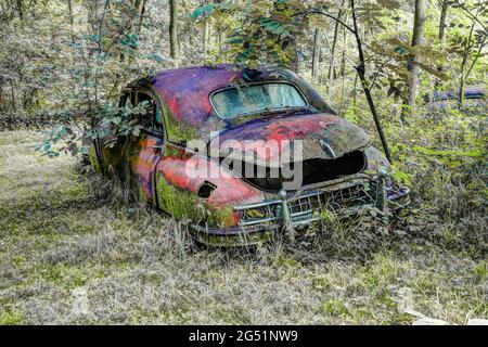 Viejo coche oxidado abandonado en el bosque