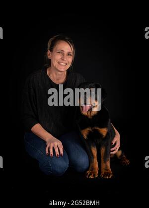 purebred rottweiler y mujer delante de fondo negro