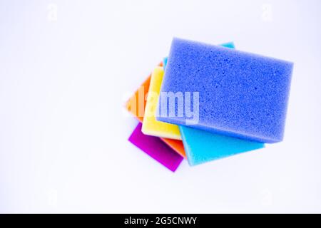 Vista superior de esponjas para lavar platos, sobre fondo blanco, aisladas. Coloridas esponjas de arco iris multicolores que se ponen unas a otras. Espacio de copia. Foto de stock