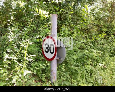 Poste corto montado 30 millas por hora señal de límite de carretera en un entorno rural Foto de stock