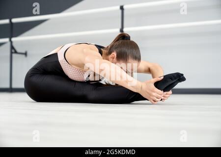 Joven mujer atractiva en ropa deportiva se estira antes de hacer