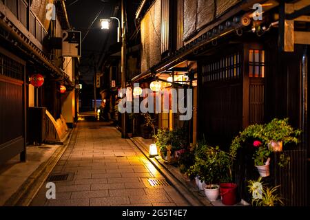 Kyoto, Japón - 16 de abril de 2019: Calle estrecha y vacía en el distrito de Gion en la noche oscura con lámparas de papel de linternas rojas iluminadas en la entrada Foto de stock
