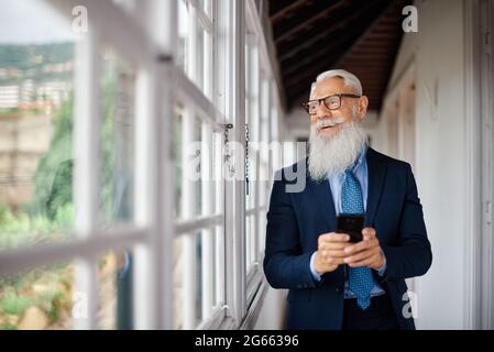 Hombre de alto nivel de hipster de negocios utilizando teléfono móvil dentro de la oficina moderna - Foco en la cara