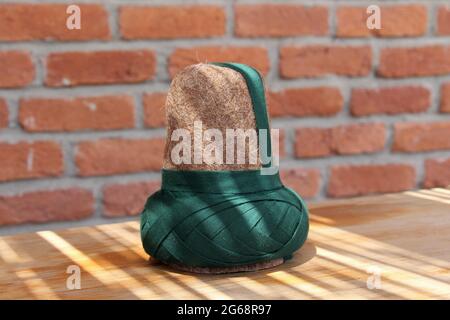 Un sombrero hecho de fieltro usado por los derviches giradores. El sombrero marrón usado por los derviches de Mevlevi. Hay una pared de ladrillo en el fondo. Foto de stock