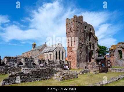 Las ruinas del Priorato medieval de Lindisfarne con la Iglesia de Santa María detrás, Isla Santa, Northumberland, Inglaterra, Reino Unido Foto de stock