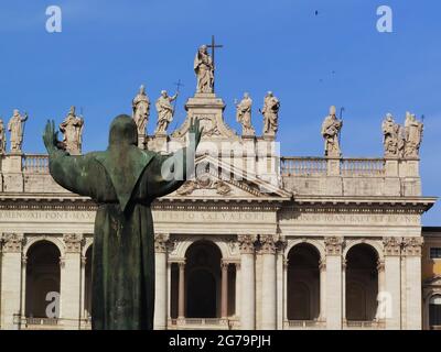 Estatua de San Francisco con los brazos abiertos mirando hacia la fachada de la catedral de Roma, San Giovanni in Laterano Foto de stock