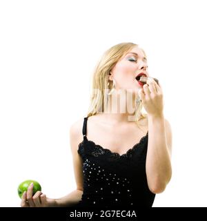 Comida y nutrición saludable - Chica rubia disfrutando de una barra de chocolate y haciendo caso omiso de una manzana Foto de stock