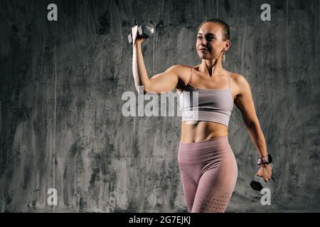 Atlética mujer deportiva posando con pesas.