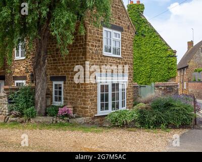 Escena callejera en el pueblo de Wootton, Northampton, Reino Unido; casa atractiva construida de piedra local. Foto de stock