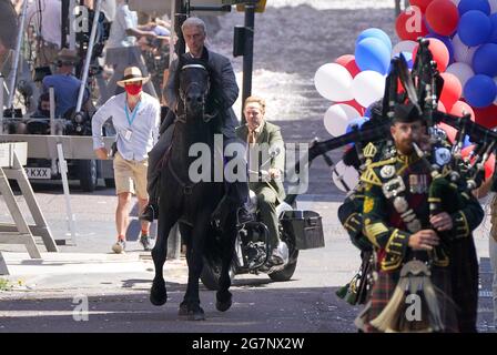 El doble del cuerpo para Harrison Ford y Boyd Holbrook se ven en un caballo y moto durante una escena de desfile en St Vincent Street en Glasgow, durante el rodaje de lo que se cree que es la nueva película de Indiana Jones 5 protagonizada por Harrison Ford. Fecha de la foto: Jueves 15 de julio de 2021. Foto de stock
