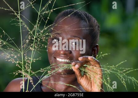 retrato de una joven hermosa y sonriente que se encuentra detrás de las plantas silvestres en la naturaleza Foto de stock