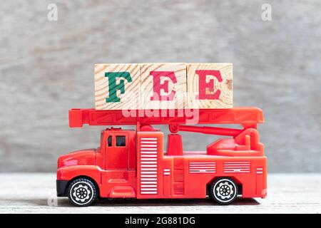Camión de bomberos rojo mantener el bloque de letras en palabra de pago sobre fondo de madera Foto de stock
