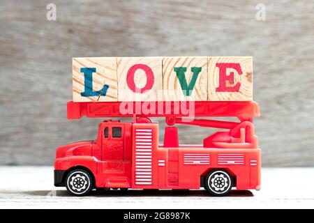 Juguete escalera de fuego camión sostener el bloque de letras en palabra amor sobre fondo de madera Foto de stock
