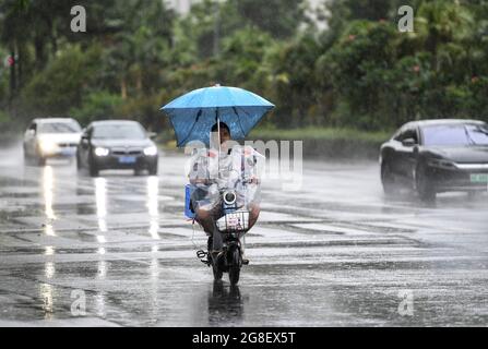 (210720) -- SHENZHEN, 20 de julio de 2021 (Xinhua) -- un residente monta una bicicleta eléctrica bajo la lluvia en Shenzhen, provincia Guangdong del sur de China, 19 de julio de 2021. Según las autoridades meteorológicas provinciales, se prevé que el tifón Cempaka, el séptimo de este año, se derrumbe el martes en la costa de la provincia china de Guangdong, en el sur de China. Cempaka, fortaleciéndose en un tifón el lunes por la mañana, se acercará lentamente a la región costera entre el estuario del río Pearl y el oeste de Guangdong, con su intensidad aumentando gradualmente, y hará tierra entre las ciudades de Zhuhai y Maoming entre Mar Foto de stock