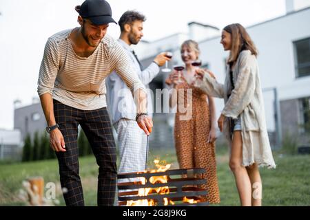 Los amigos tienen un picnic con barbacoa en el patio trasero Foto de stock
