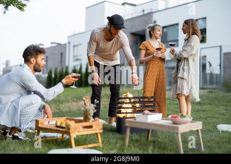 Los amigos tienen un picnic con barbacoa en el patio trasero Foto de stock