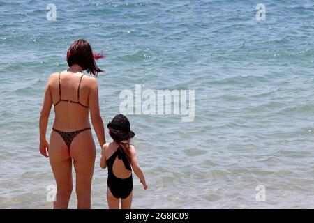 Mujer en el bikini que lleva a la niña niño al Mamá con hija pequeña en una playa de arena, concepto de vacaciones de verano Fotografía - Alamy