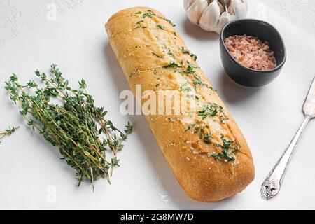 Conjunto de mantequilla de hierbas compuesta rellena de pan de ajo, sobre fondo de mesa de piedra blanca Foto de stock