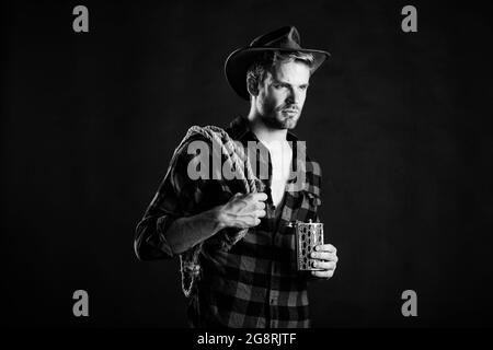 Hombre campesino vaquero en el lado del país con sombrero vaquero  occidental. Modelo masculino americano en el campo. Hombre atractivo con  whisky o brandy Fotografía de stock - Alamy