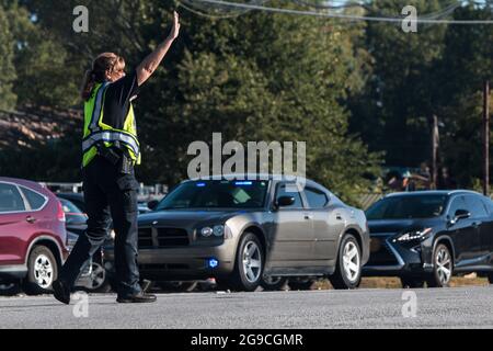 Suwanee, GA, EE.UU. - 21 de septiembre de 2019: Una oficial de policía femenina pone su mano para detener el tráfico, mientras dirige el tráfico de vehículos en un festival de otoño. Foto de stock
