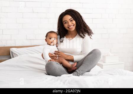 Feliz African American Madre abrazando Holding Niño Niño Interior