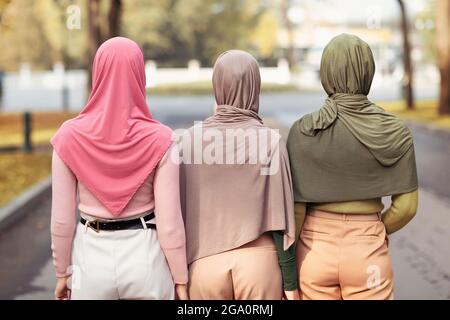 Vista posterior de tres mujeres musulmanas que llevan hijabs Caminando juntas afuera
