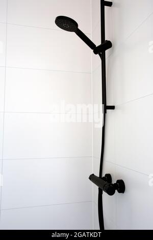 Cerca de la moderna y elegante alcachofa de ducha negra y el baño