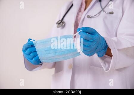 Un médico que sostiene una máscara quirúrgica en la mano. Foto de stock