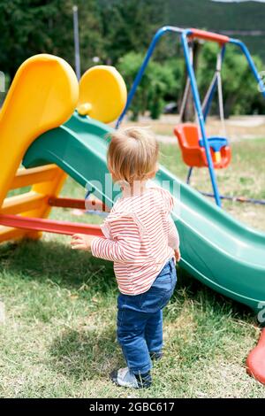 Parque infantil con columpio para bebés y deslice cerca de casas Fotografía  de stock - Alamy