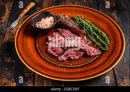 Onglet asado a la parilla carne tierna carne filete de ternera en un plato. Fondo de madera oscura. Vista superior Foto de stock