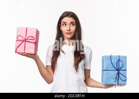 Celebración, vacaciones y presenta el concepto. Retrato de cintura-up de chica joven linda, soñadora preguntándose qué de regalo más pesada, pesando regalos en Fotografía stock - Alamy