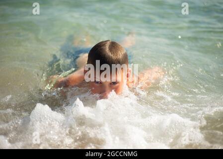 El niño nadará en el mar. Cara en espuma de mar. Emociones satisfechas. Placer Foto de stock