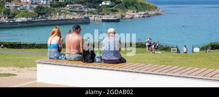 Una imagen panorámica de los turistas que se encuentran en una estancia relajándose bajo el sol en Killacourt con vistas a la bahía de Newquay y al puerto de Newquay Foto de stock