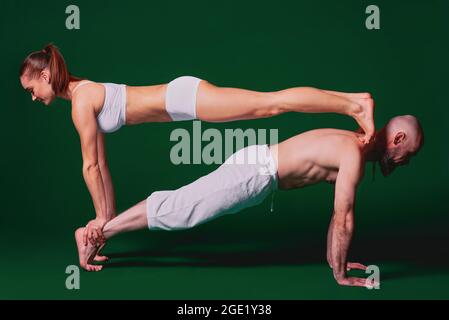 retrato de una pareja deportiva hermosa: mujer y hombre con ropa blanca  haciendo asanas de yoga juntos en el interior Fotografía de stock - Alamy