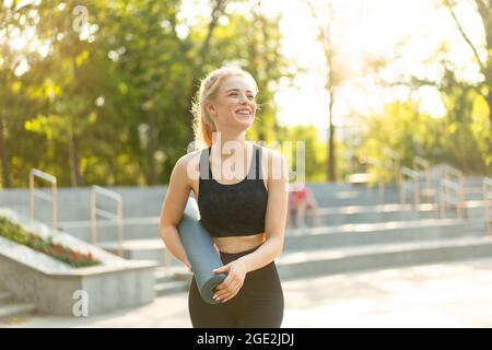 Deportiva mujer delgada ropa deportiva leggings negros y top standing cerca  de escaleras de hormigón sosteniendo