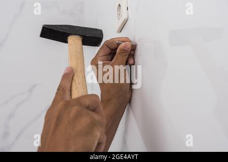 Las manos del hombre martillando un clavo en una pared