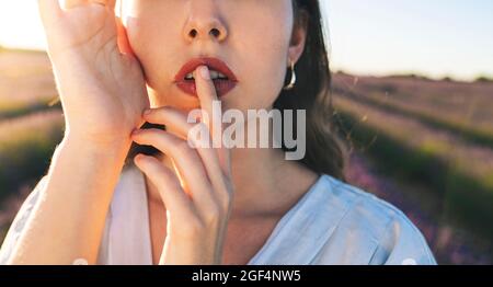 Mujer joven con el dedo en los labios en el campo Foto de stock