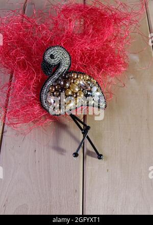 Un hermoso broche de flamencos a mano, bordado con abalorios, lentejuelas y sobre una nube de hilos rojos. Fondo leñoso Fotografía stock - Alamy