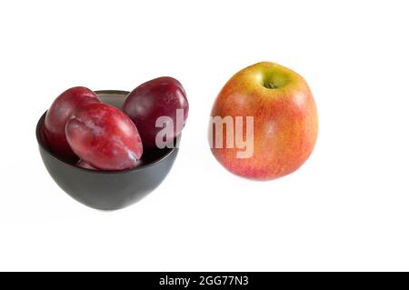 Ciruelas y manzana del huerto sobre fondo blanco. Foto de stock