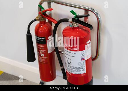 Un par de extintores rojos - agua y dióxido de carbono - en un estante de apoyo en una oficina, Reino Unido Foto de stock