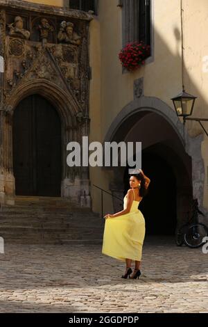 Regensburg Altstadt oder Innenstadt oder City mit schwarzhaariger Schönheit mit sinnlichen Blick und gelben Kleid. Oberpfalz, Bayern, Regensburg. Foto de stock