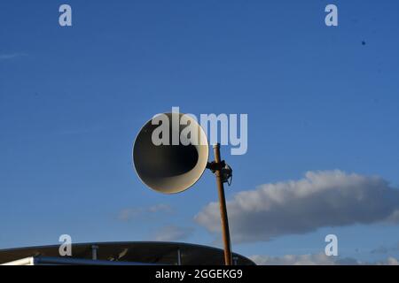 Un antiguo megáfono de estilo retro con el telón de fondo de un cielo azul con nubes sombreadas Foto de stock