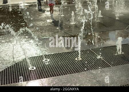Chorros de la fuente en la plaza de la ciudad. Chorros de agua en verano. Salpicaduras de la fuente del suelo. Foto de stock