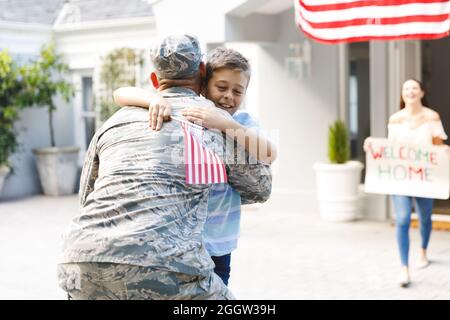 Soldado macho caucásico con hijo y esposa casa exterior decorada con bandera americana Foto de stock
