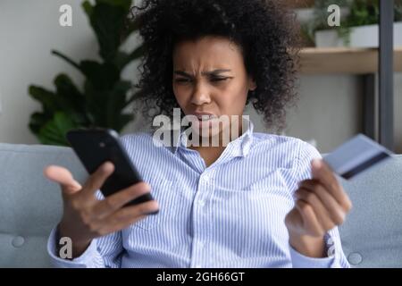 Mujer negra joven que tiene problemas con pagar en línea por tarjeta Foto de stock