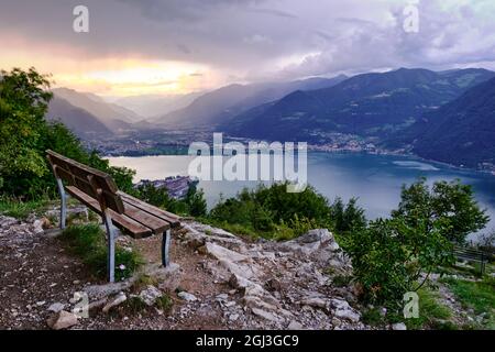 Puesta de sol sobre el lago, las montañas y banco vacío, Lago Iseo, Lombardía, Italia Foto de stock