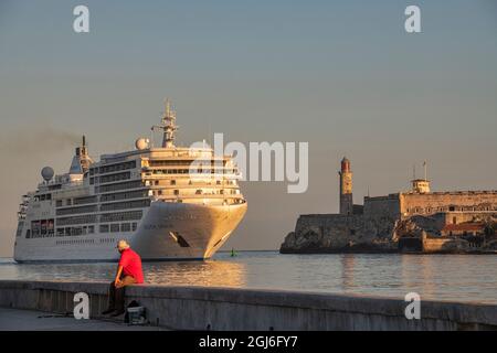 El hombre observa a un crucero pasar barcos de pesca y la fortaleza del Castillo de Los Tres Reyes Del Morro a la entrada de la bahía de Habana, Cuba Foto de stock