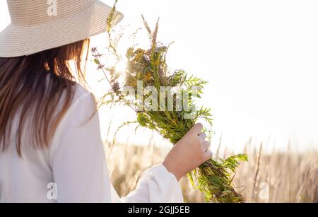 Retrato de estilo de vida de verano de una mujer que sostiene un ramo de flores de campo, hierbas. Ella está de pie en un campo de grass.Felicidad y concepto de amor. Copia s Foto de stock